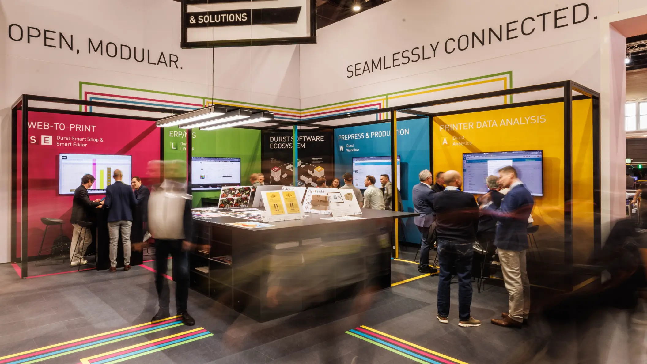 Durst, bunter Software-Bereich des Messestandes auf der FESPA 2025 mit einigen Besucherinnen und Besuchern
